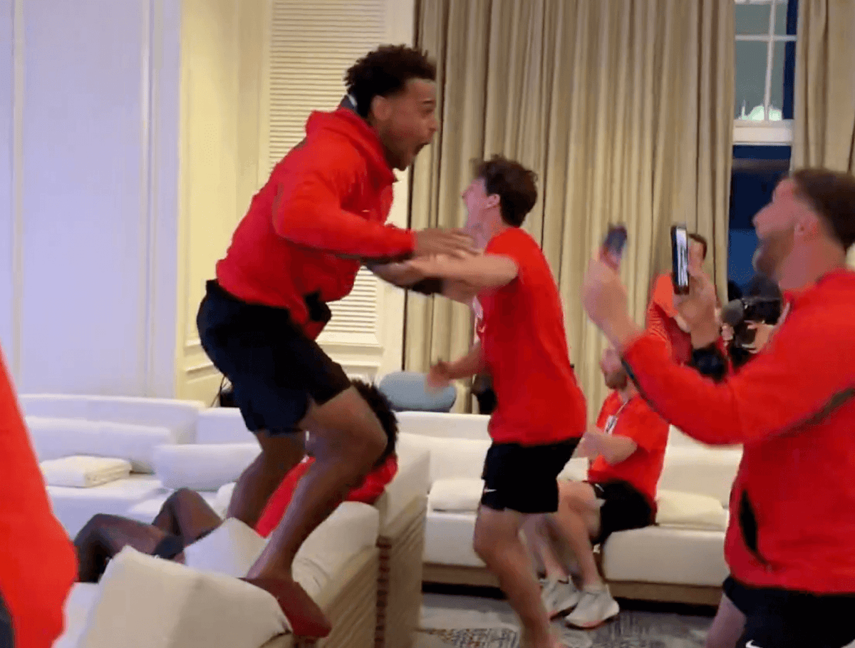 USMNT players gathered in a hotel room, excitedly watching an NBA game on a projector screen.