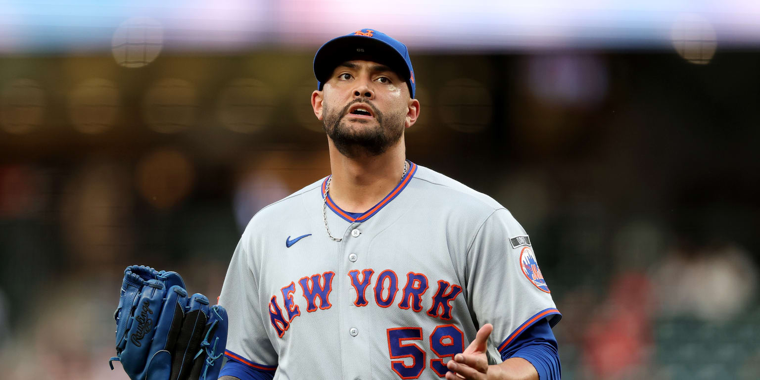 A baseball player in a New York Mets uniform swings a bat during a game.