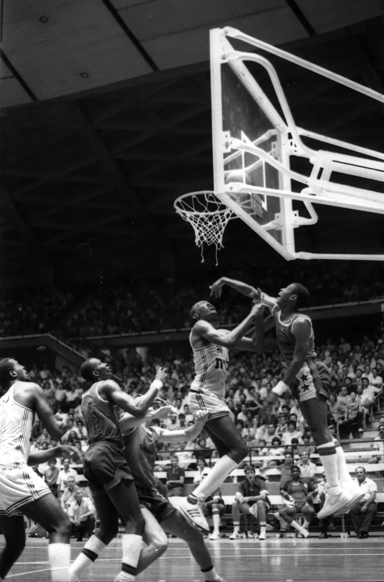 A dynamic image of NBA players competing on the court during a close game, with a background graphic of NBA team logos and standings.